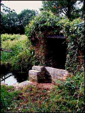 Cette fontaine a l&rsquo;allure d&rsquo;un puits avec un b&acirc;tis carr&eacute; en moellons de schiste 