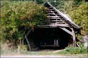 ossature de ce hangar est faite avec des poteaux en bois. L&rsquo;ouverture principale fait face au chemin pour faciliter la sortie des charrettes. La partie sup&eacute;rieure de cette ouverture est en planches ajour&eacute;es point&eacute;es sur la charpente. Les c&ocirc;t&eacute;s et le fonds sont en partie en palis et en partie en planches mal &eacute;quarrie